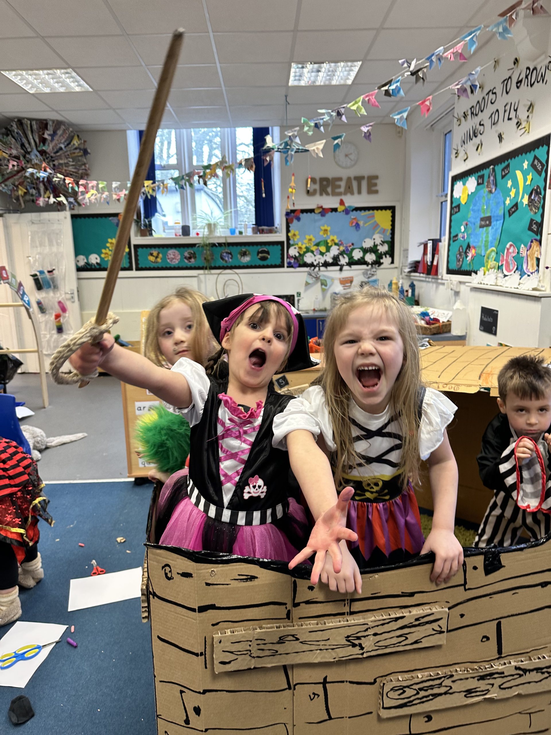 Children enjoying being dressed as pirates in a pirate ship made out of cardboard.