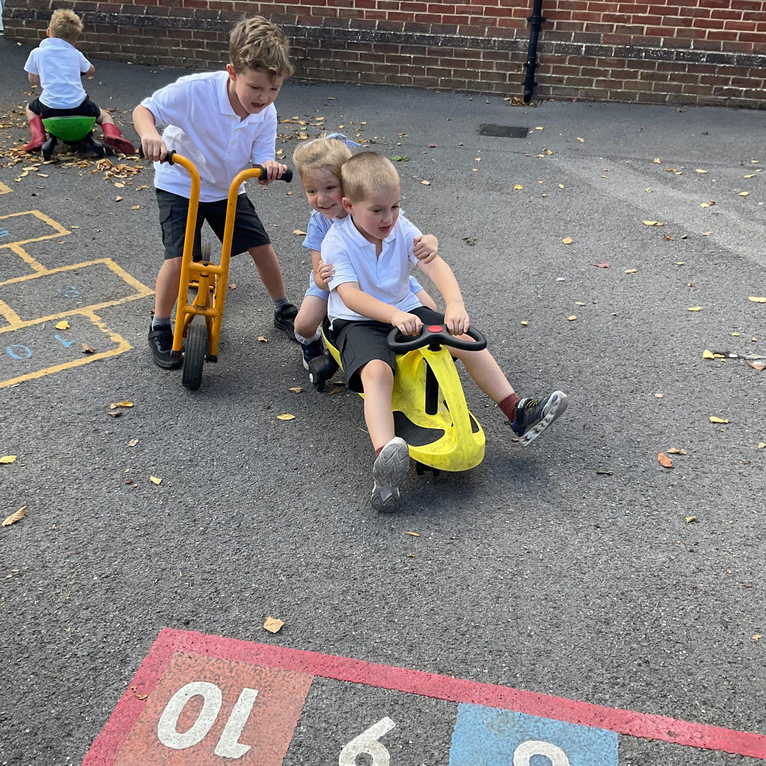 Children play on bikes and scooters in the playground.